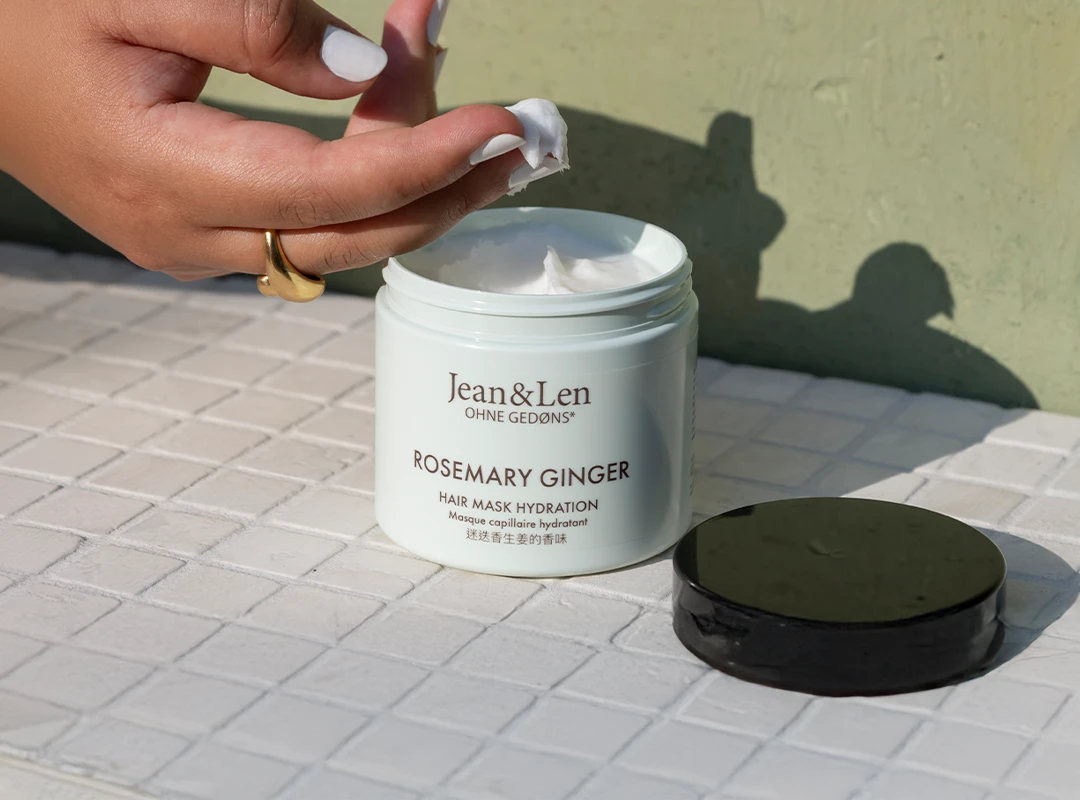 Eine feminine Hand entnimmt Haarkur aus dem Tiegel der Rosemary/Ginger Haarkur.